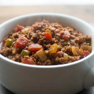 A dark bowl of hearty keto chili recipe, showing the rich, thick texture of the ground beef and red tomato sauce.