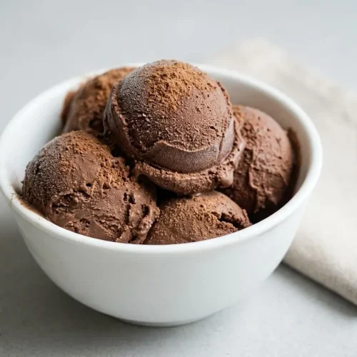 A loaf pan filled with rich, scoopable keto ice cream, showing a smooth, creamy dark chocolate texture.