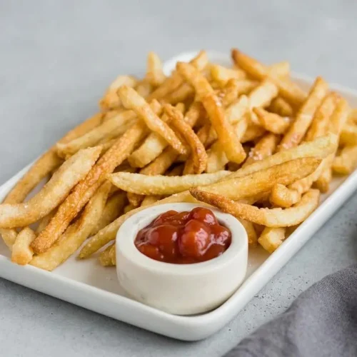 A white ceramic container filled with crispy, golden-brown Keto French Fries, ready to serve.