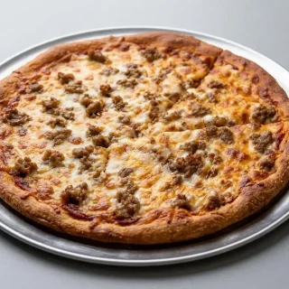 A slice of keto pizza crust with Italian sausage and melted cheese being lifted from a dark pan, showing its sturdy, golden-brown edge.