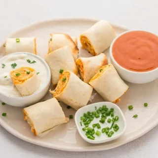 A platter of crispy Keto Buffalo Chicken Pinwheels, showing the spiral of creamy orange filling inside each golden-brown, air-fried tortilla