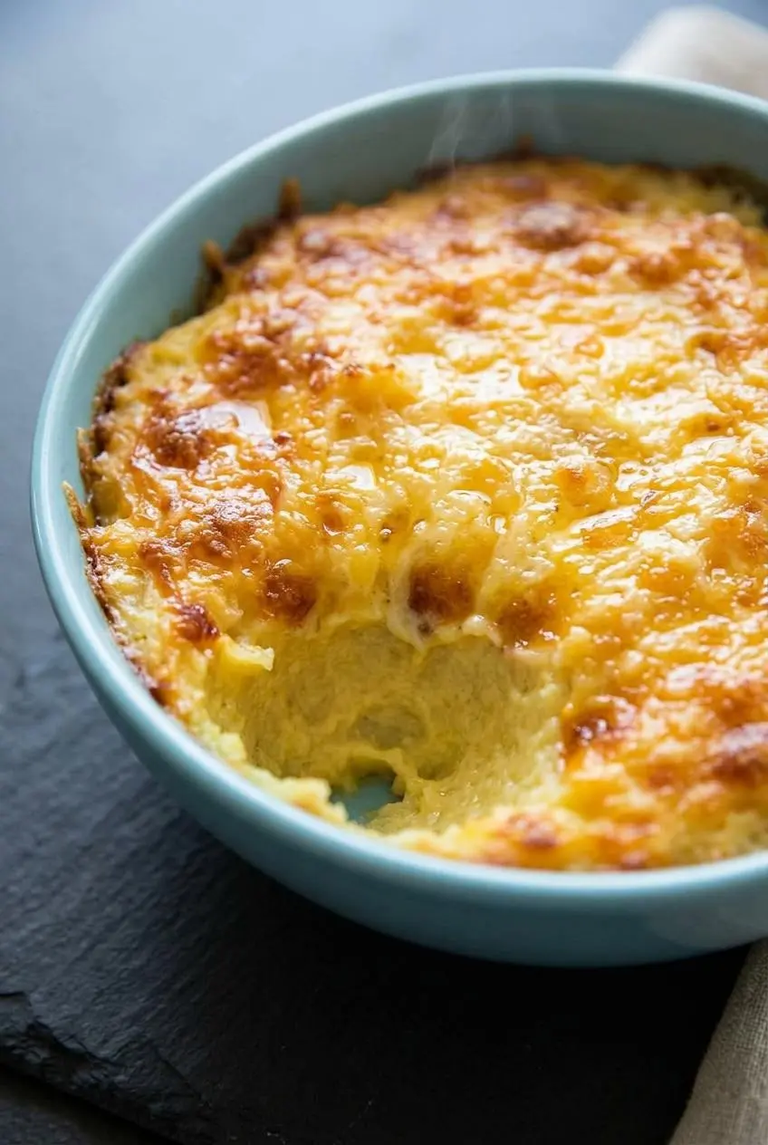 Golden brown baked cheddar and Asiago cheese crust on top of creamy mashed cauliflower in a baking dish.