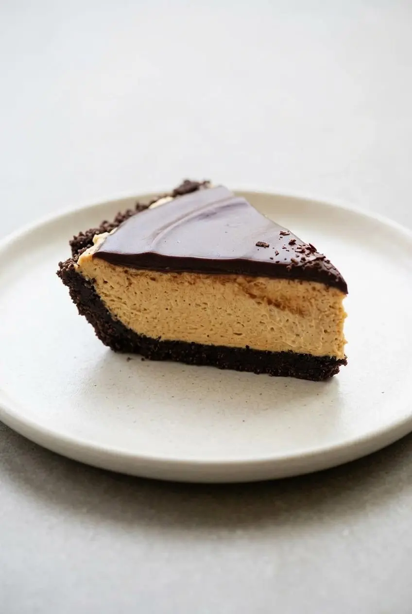Slice of keto peanut butter pie topped with a glossy sugar-free dark chocolate ganache layer.