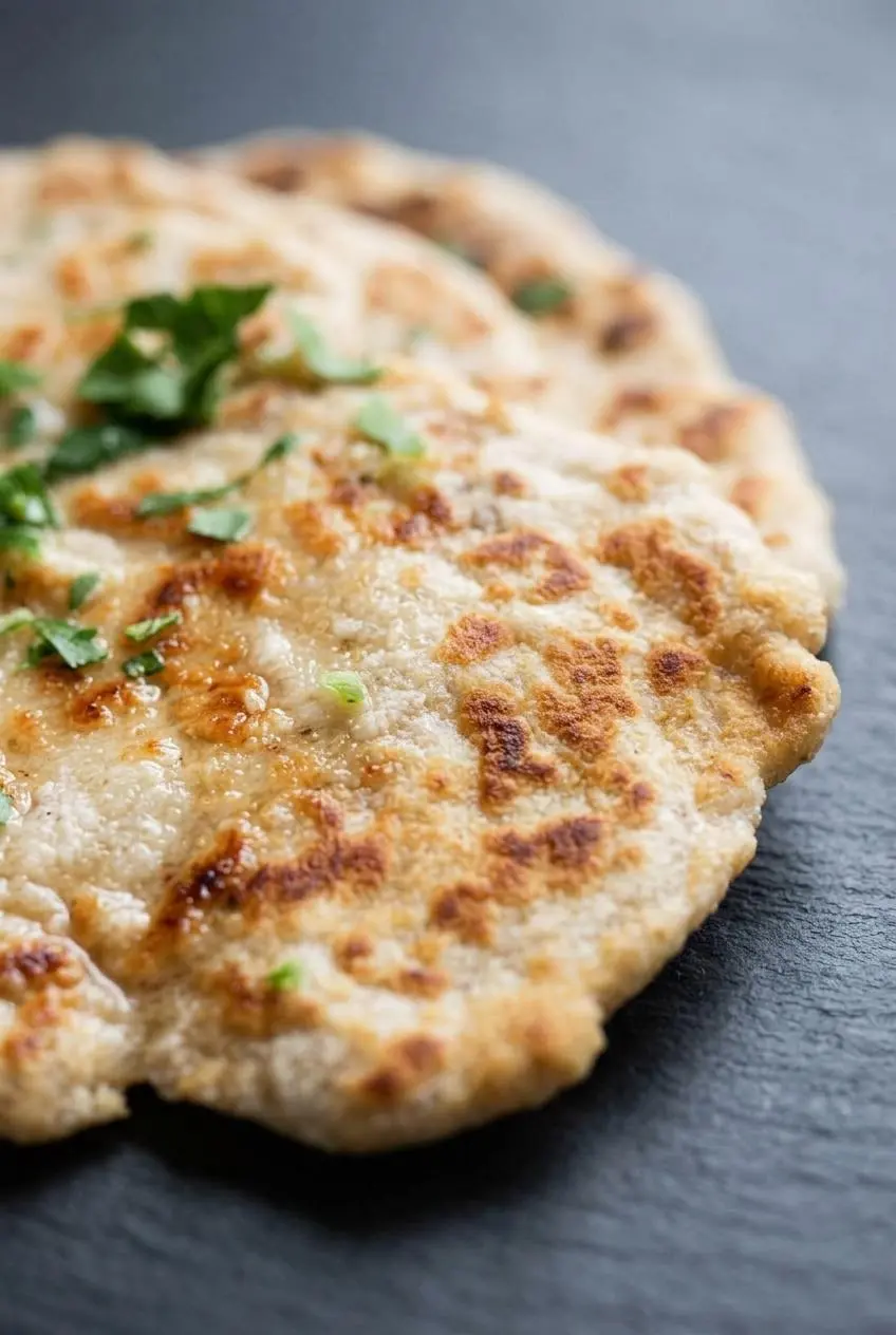 Close-up of the blistered surface of a skillet-cooked coconut flour flatbread on a slate background.