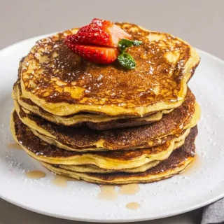 Golden keto cottage cheese pancakes stacked with tender edges and an airy, delicate texture.