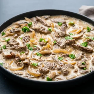 Tender strips of keto beef stroganoff with sliced mushrooms in a rich, glossy sour cream gravy.