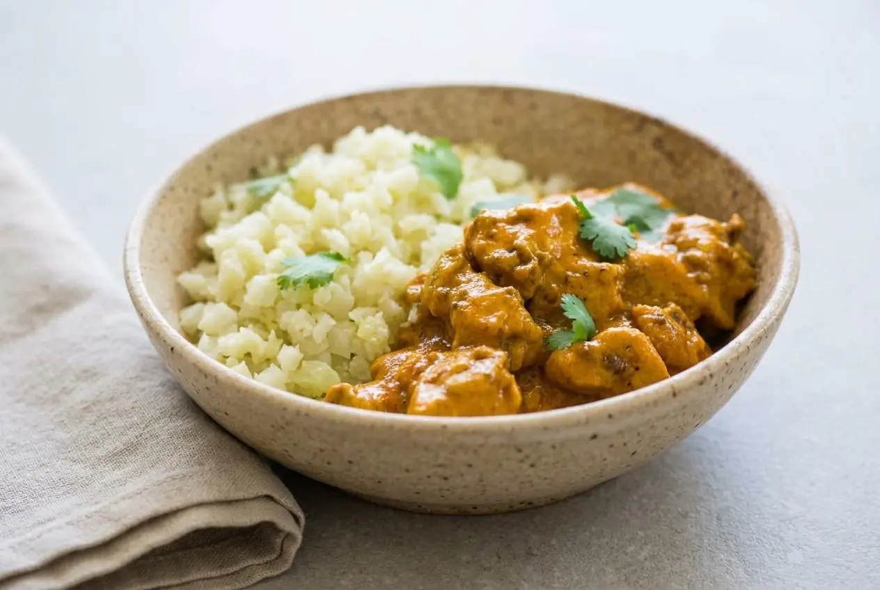 A skillet of creamy keto butter chicken recipe with tender chicken in a glossy, rich orange-gold tomato cream sauce.