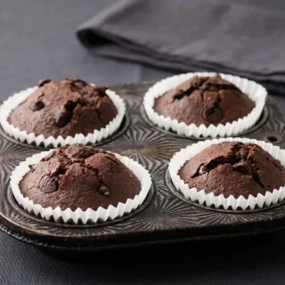 Tender baked keto chocolate muffins topped with melted sugar-free chocolate chips.