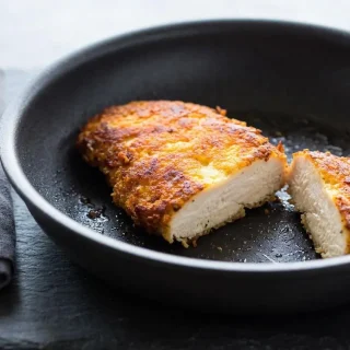 Crispy keto parmesan crusted chicken breast cutlet cooked to a golden brown.