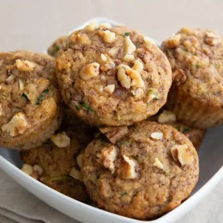 Golden baked keto zucchini muffins with tender spiced tops and visible green zucchini flecks.