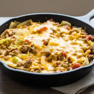 Low Carb Cheesy Cabbage Casserole in a cast iron skillet with melted cheese and savory ground beef.