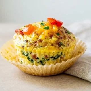 Fluffy keto egg bites baked with melted cheddar, chopped spinach, and savory bacon.