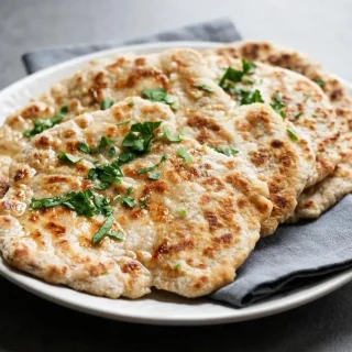 Soft and pliable keto naan bread with golden brown charred spots brushed with melted butter.