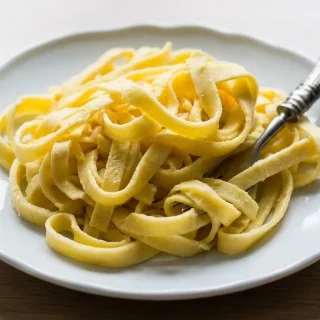 Tender, pliable keto egg noodles recipe ribbons served in a gray ceramic bowl.