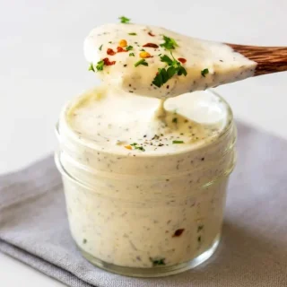 Keto ranch dressing with creamy texture and dried herb flecks in a bowl.