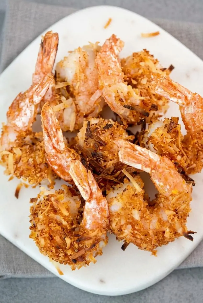 Close-up of keto coconut shrimp showing a tightly bonded toasted coconut and crushed pork rind crust.