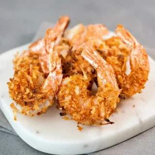 Golden crispy keto coconut shrimp with toasted coconut flakes and tails on ready for dipping.