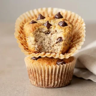 Golden keto banana chocolate chip muffins baked with almond flour and studded with melted chocolate.