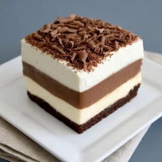 Keto chocolate lasagna square showing crisp cocoa crust, cream cheese filling, pudding, and whipped topping.