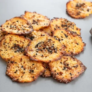 Golden keto cottage cheese chips baked crisp with deeply browned, lacy edges on parchment paper.