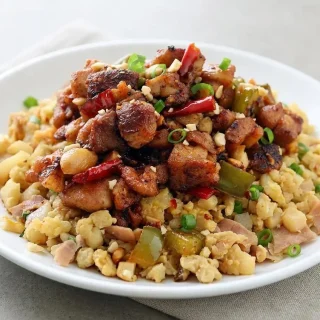 Keto kung pao chicken with glossy chili-garlic glaze, browned chicken thighs, crisp bell peppers, and roasted peanuts.