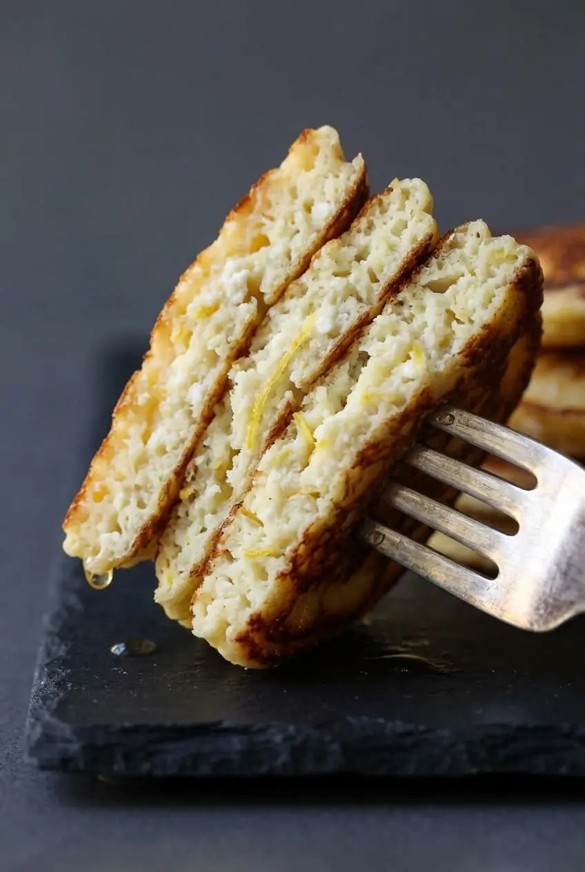 Tender keto lemon ricotta pancake split open with a fork to show moist, fluffy crumb.
