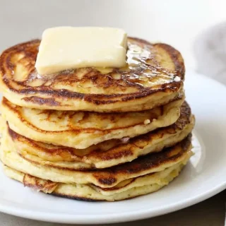 Fluffy keto lemon ricotta pancakes stacked with golden brown edges and fresh citrus zest.