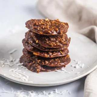 Keto no bake cookies set into rich chocolate mounds with shredded coconut and a firm matte finish