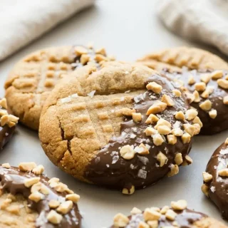 Golden keto peanut butter cookies with crisp edges and classic fork marks on a baking sheet.