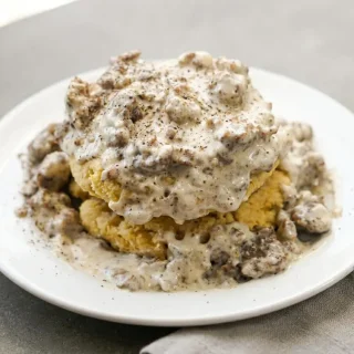 Velvety keto sausage gravy recipe with browned pork crumbles and cracked black pepper in a warm skillet.