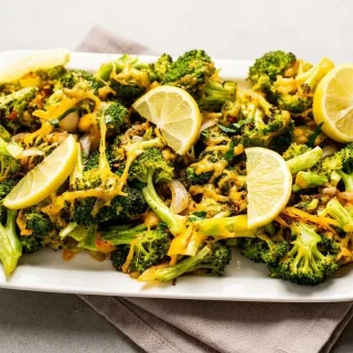 Keto sauteed broccoli topped with melted cheddar cheese and caramelized shallots.