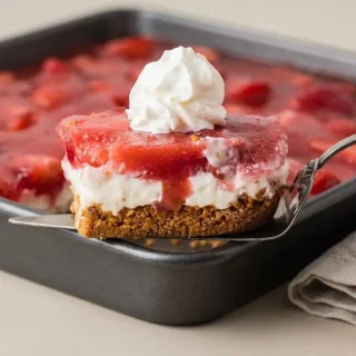 Keto strawberry pretzel salad slice featuring crisp crust, rich cream cheese, and glossy fruit gelatin layer.