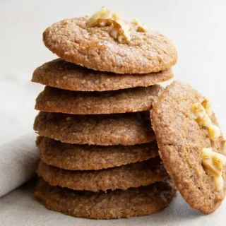 Freshly baked keto banana cookies topped with crushed walnuts and lightly browned edges.