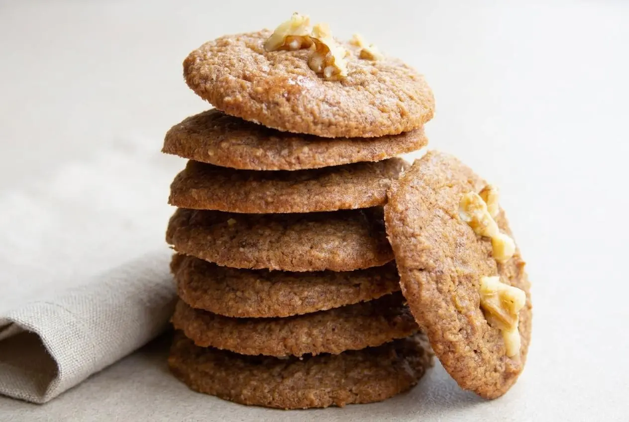 Freshly baked keto banana cookies topped with crushed walnuts and lightly browned edges.