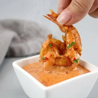 Keto bang bang shrimp with a crisp golden coating drizzled in creamy spicy sauce.