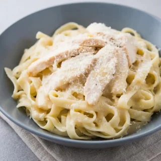 Rich and silky keto alfredo sauce recipe with a glossy Parmesan finish in a warm skillet.