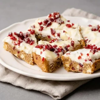 Triangle-cut keto cranberry bliss bars with creamy frosting, dried cranberries, and glossy white chocolate drizzle