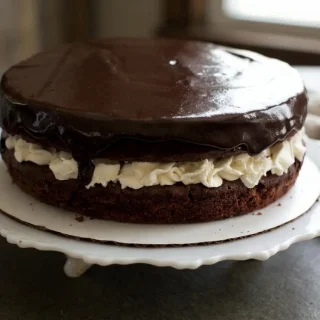 Keto ding dong cake with dark chocolate layers, thick white cream filling, and glossy fudge ganache.