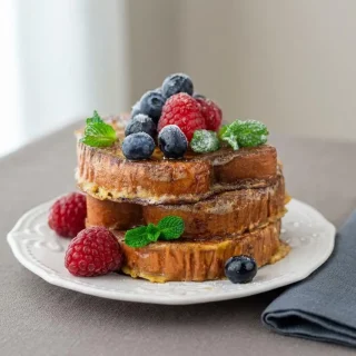 Keto french toast recipe slices showing a golden-brown buttered crust and soft cinnamon custard center.