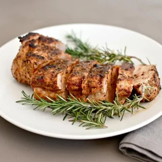 Juicy keto pork tenderloin sliced to show a golden herb crust and tender center.