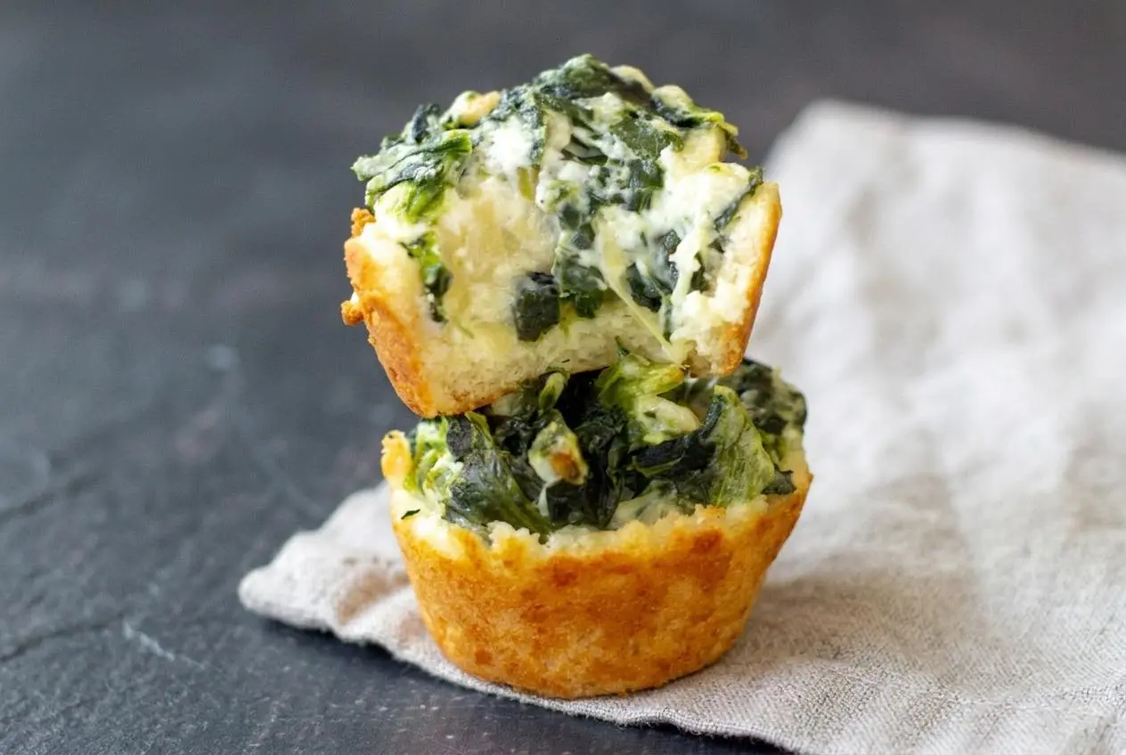 Baked keto spinach artichoke dip bites with golden cheese dough crusts and creamy Parmesan-topped filling